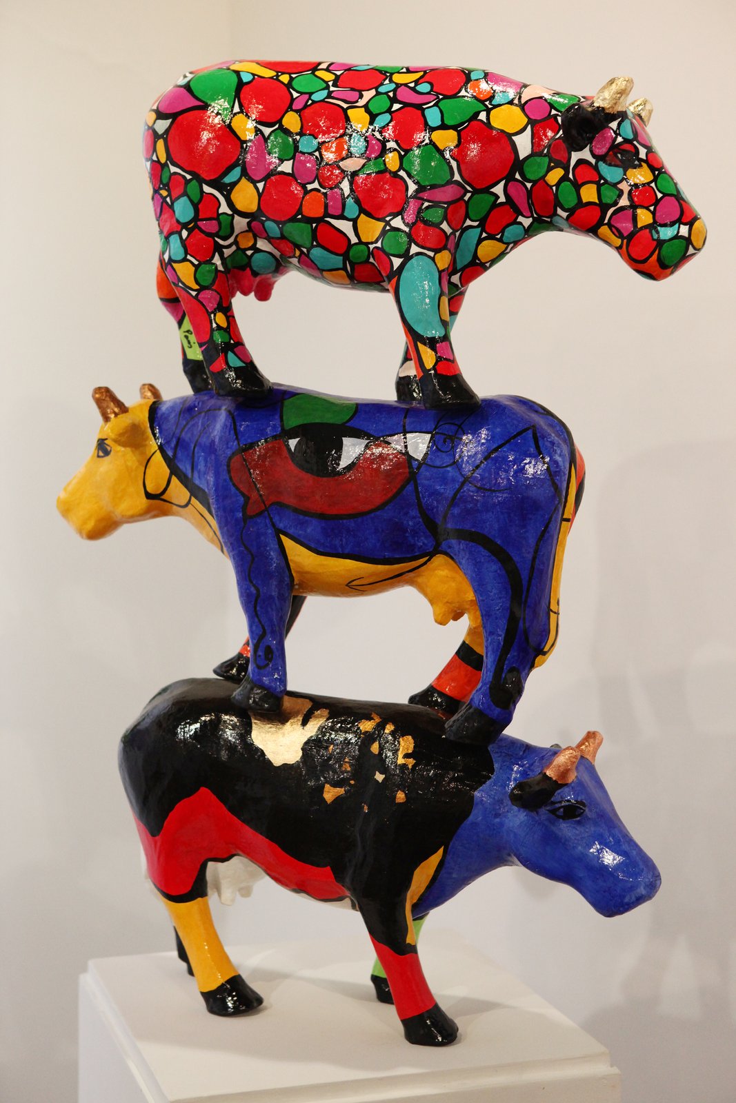 Escultura de três vacas coloridas empilhadas